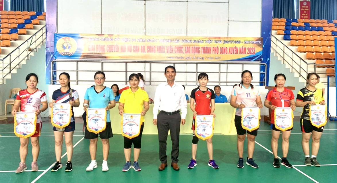 Chủ tịch LĐLĐ TP Long Xuyên Trương Văn Chiêm tặng cờ kỷ niệm cho đại diện 8 đội tham dự Giải bóng chuyền hơi nữ kỷ niệm 94 năm Ngày thành lập Công đoàn Việt Nam. Ảnh: Lâm Điền